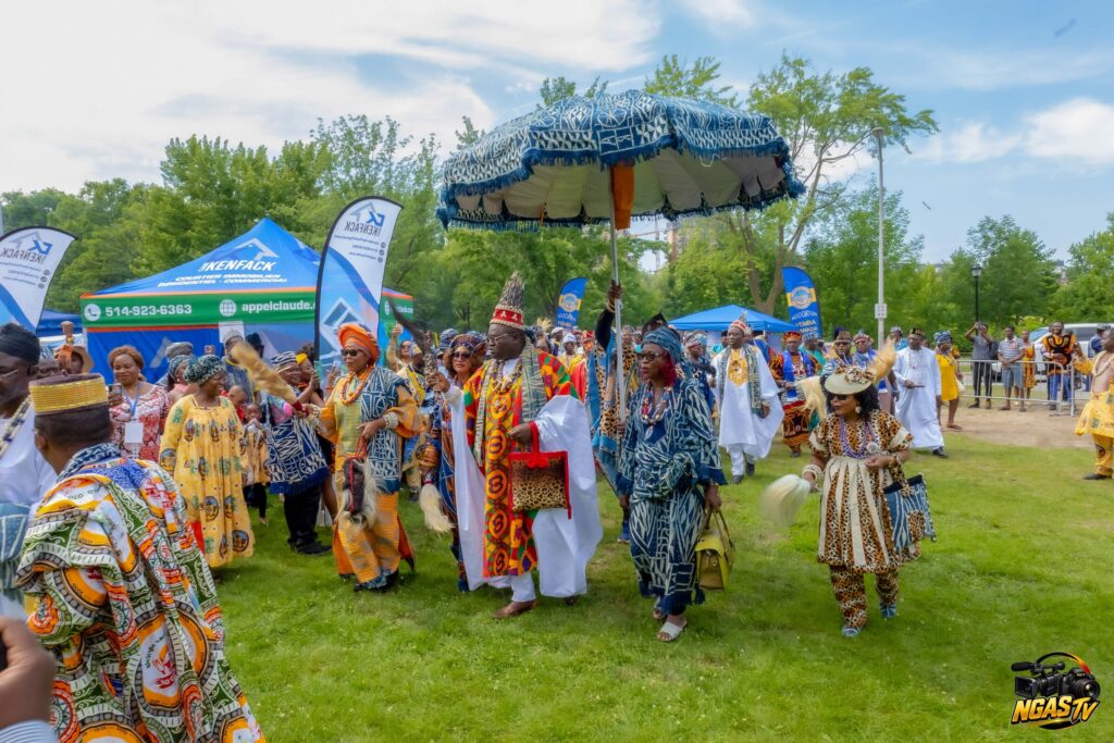 Festival Yemba Canada 2026 : cortège avançant sur la pelouse sous une grande ombrelle en tissu ndop